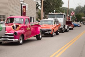 Photograph of a car show lined up down the street.
