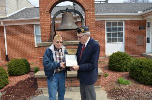 Photograph of a veteran receiving an award in front of the liberty bell.