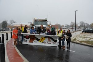 Photograph of a plow with community members standing around it.